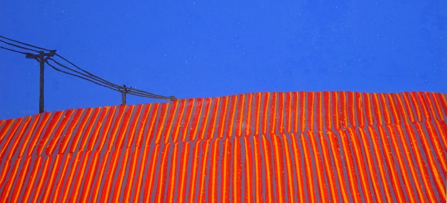 red field contrasting with bright blue sky. Telegraph cables in distance