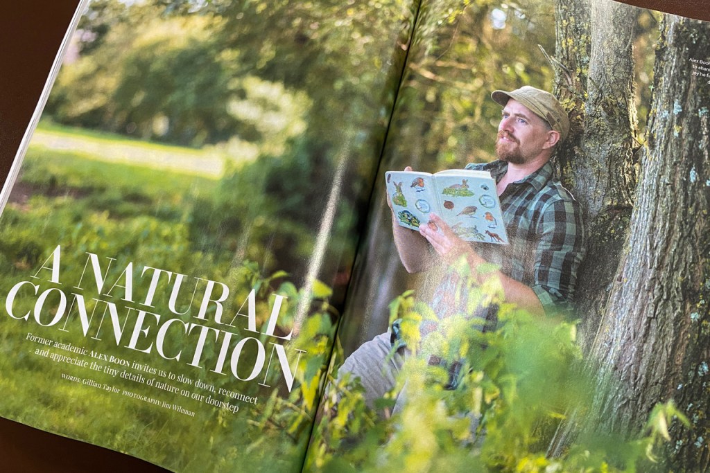 A glossy magazine opened to show a large photo of an artist. He is leaning against a tree sketching. The headline reads 'A Natural Connection'